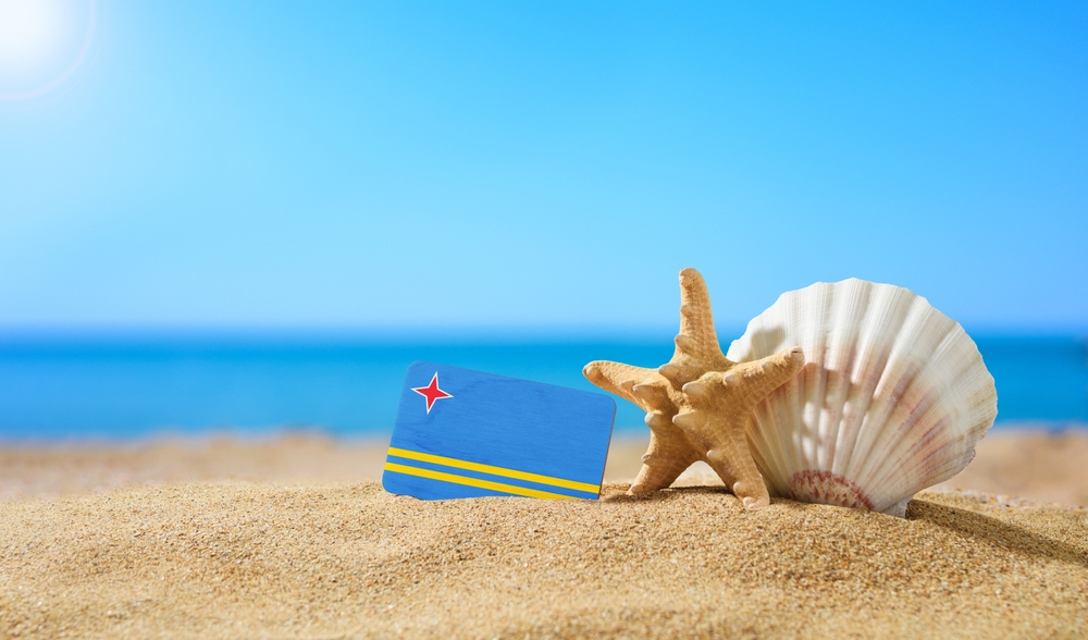 Close up of Aruba sandy beach with starfish, seashell, and card with Aruba flag